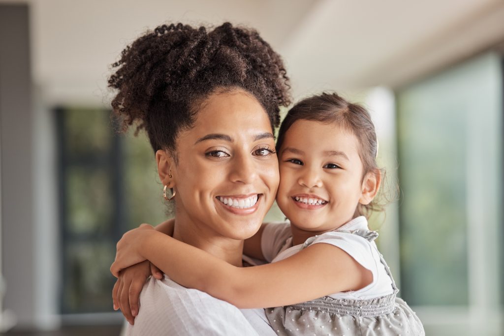 Family, love and bond of mother and daughter sharing a hug, happiness and having fun on mothers day in their puerto rico home. Portrait and smile of woman and foster girl child bonding after adoption